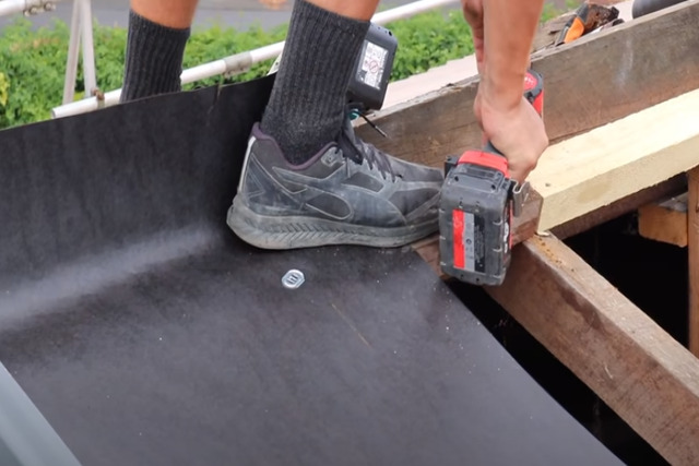 Roofing worker nailing the wood on the roof